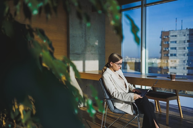 Successful young business woman in glasses with laptop in office Business woman sending email message and working on laptop Young business woman sitting at workplace