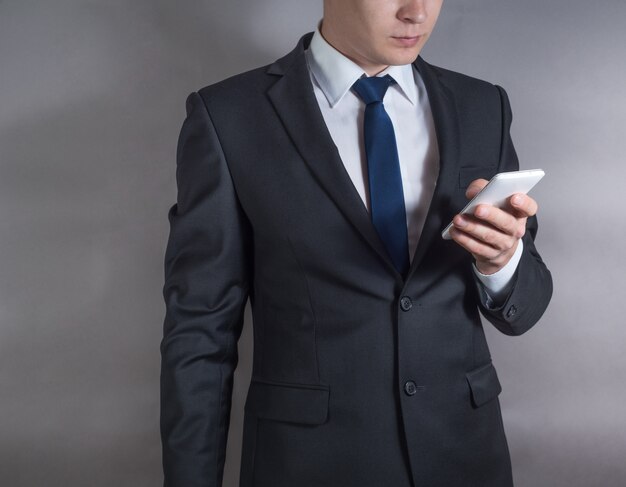 Successful young businessman in black suit using mobile phone