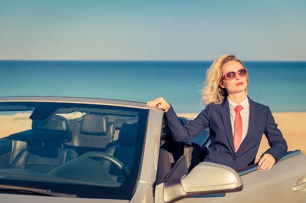 Successful young businesswoman on the beach Woman standing near the cabriolet classic car