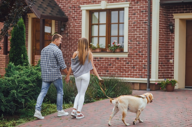 Successful young couple walking with a dog near home.