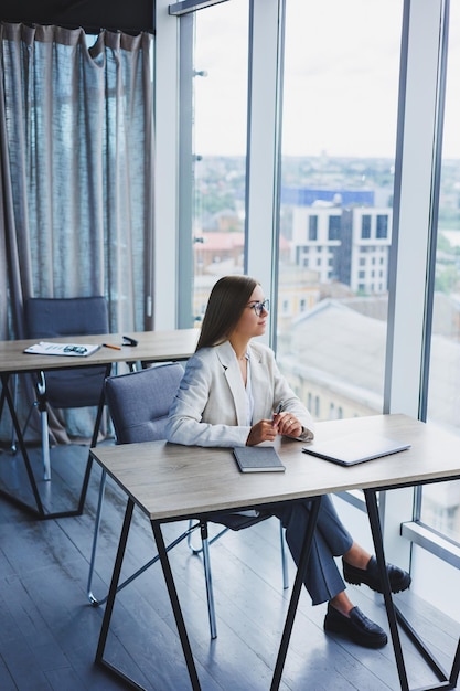 Successful young female manager in an elegant casual jacket and optical glasses sits in the office at the workplace an experienced woman with a modern laptop working in the office