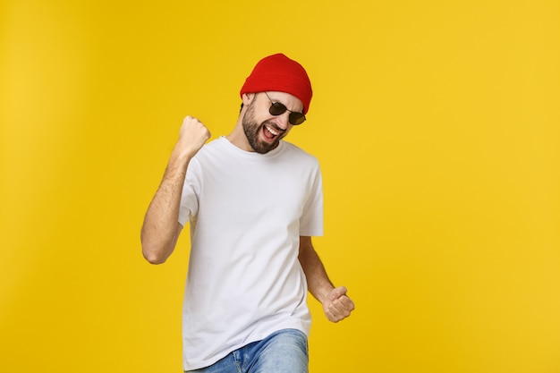 Successful young man celebrating against a yellow.