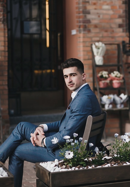 Successful young man dressed in an expensive suit is sitting in the city