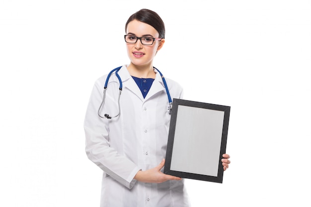 Successful young woman doctor with stethoscope holding frame in her hands in white uniform