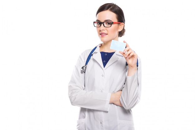 Successful young woman doctor with stethoscope with arms crossed showing business card in white uniform