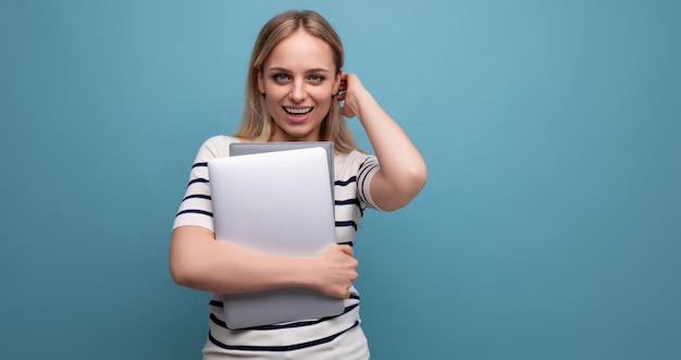 Successful young woman student with a closed laptop in her hands on a blue isolated background