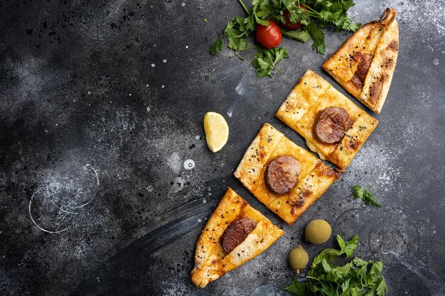 Photo sucuklu pide turkish sausage pizza on black dark stone table background top view flat lay with copy space for text