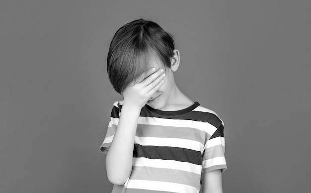 Suffering migraine Headache because stress Black and white Portrait of a sad boy holding his head with his hand Little boy having a headache Despair tragedy Headache child