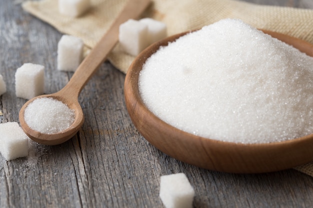 Sugar background. Sugar cubes, granulated sugar in spoon and plate. White sugar on gray galvanized iron background. Copy space.