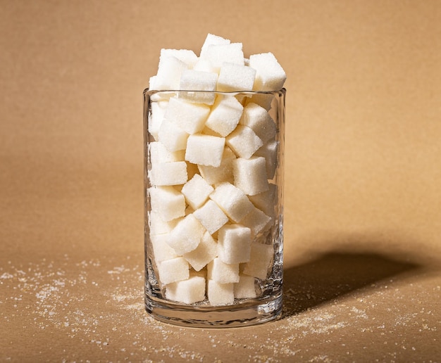 Sugar consumption addiction concept Refined cubes sweet lumps in glass Sugary food