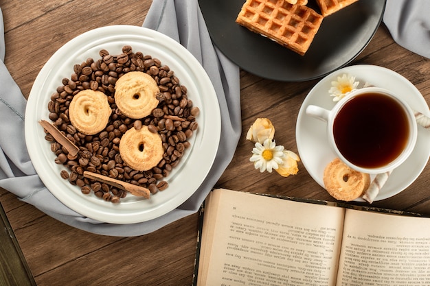 Sugar cookies on coffee beans on a saucer and a cup of tea.