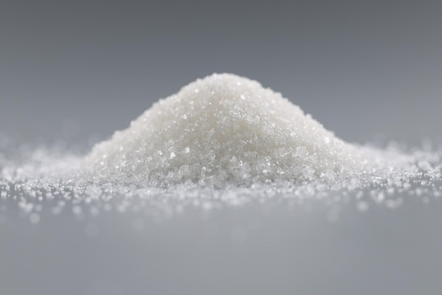 Sugar crystals pile on grey background focus on heap of sweet powder