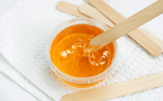 Sugar paste or wax honey in a transparent jar on a white background. Sugaring. Depilation and beauty concept. Waxing.