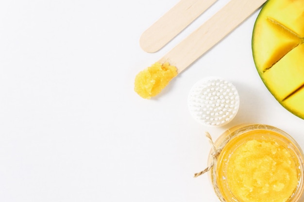 Sugar scrub skin peeling brush mango on a white wooden background with copy space top view