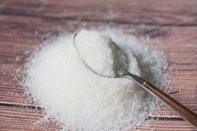 Sugar on spoon and wooden background white sugar for food and sweets dessert candy heap of sweet sugar crystalline granulated