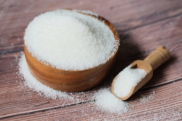 Sugar on spoon and wooden bowl white sugar for food and sweets dessert candy heap of sweet sugar crystalline granulated