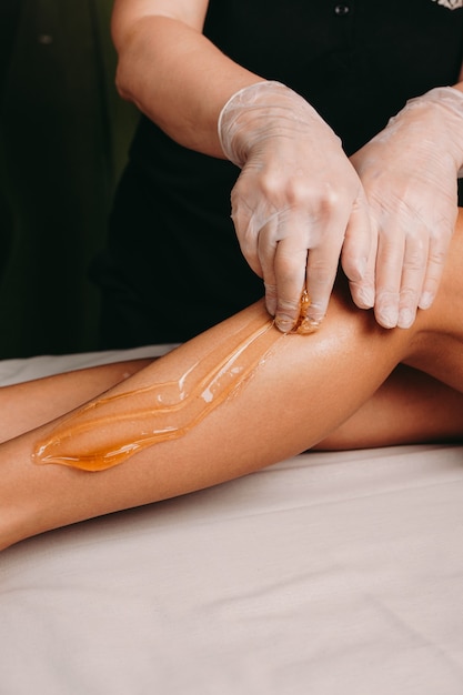 Sugaring procedure on legs done by a spa specialist during a procedure at the salon