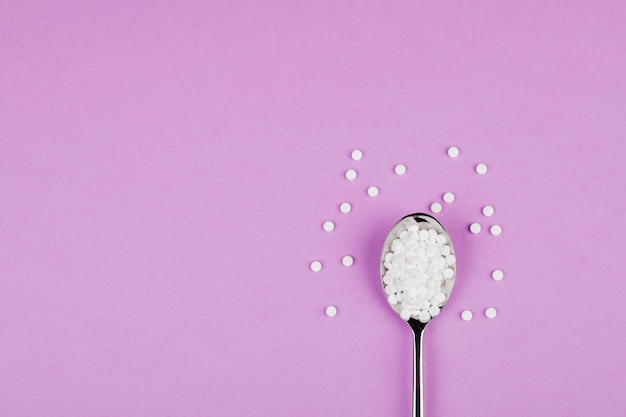 Sugarreplacing tablets with a spoon on a purple background