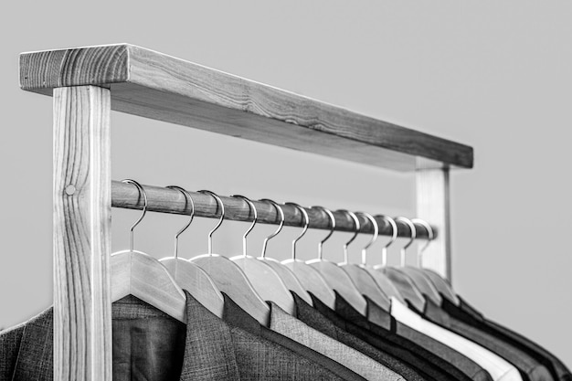 Suits for men hanging on the rack Mens suits in different colors hanging on hanger in a retail clothes store closeup Black and white