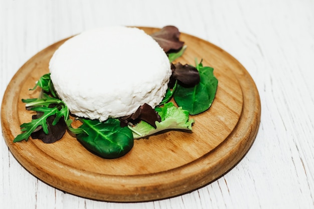 Suluguni pickled cheese on a wooden board with herbs