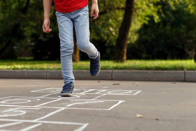 Summer activities for children. Boy playing hopscotch.