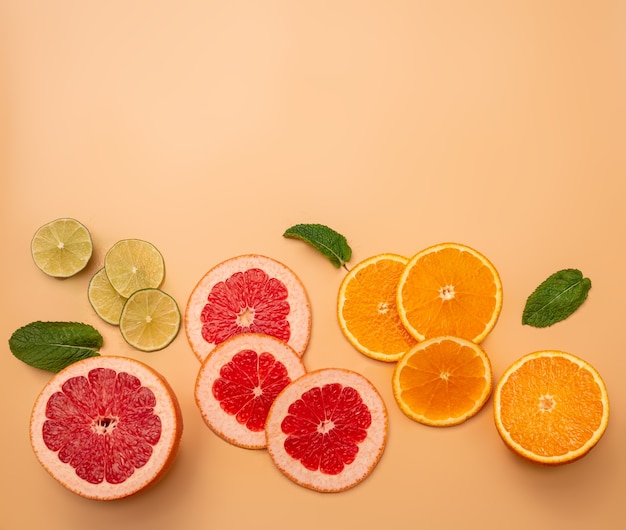 Summer background concept sliced orange, grapefruit, lemon, lime, mint on orange background