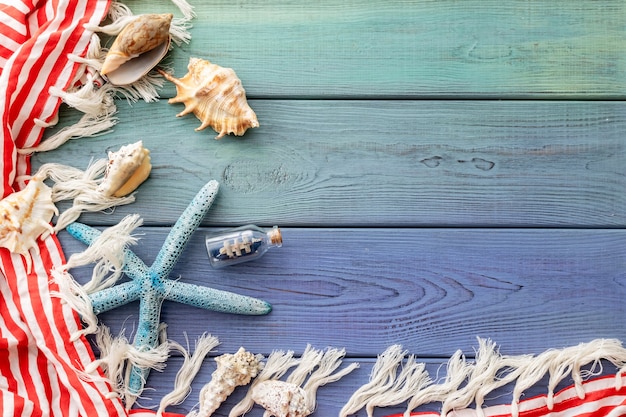 Summer background fringed pareo, seashells, boat in a bottle, starfish on a blue wooden background