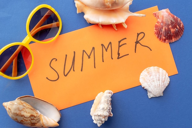 Summer background inscription summer on an orange envelope, sunglasses, seashells 