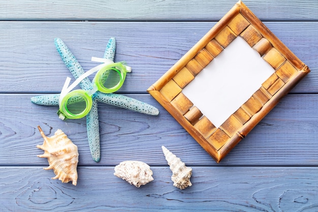 summer background photo frame, starfish, seashell sunglasses on blue wooden background