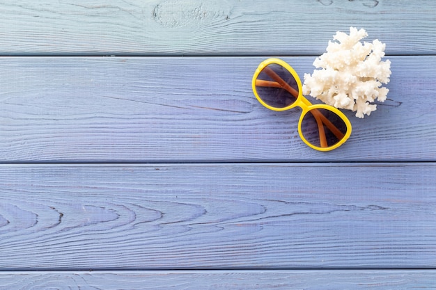 Summer background starfish, coral, seashell, sunglasses on blue wooden background