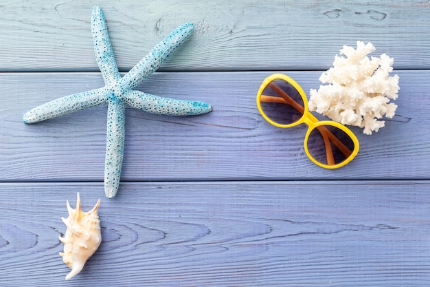 summer background starfish, coral, seashell, sunglasses on blue wooden background