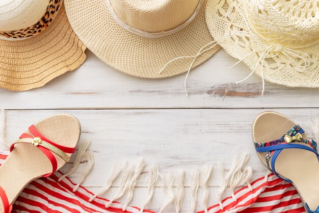 Summer background straw hat, sandals, fringed pareo on a light wooden background