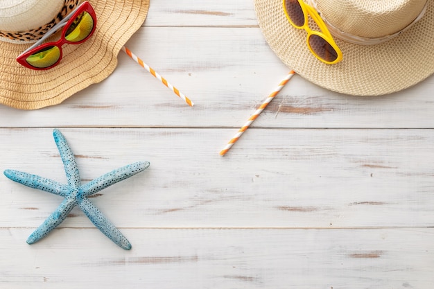 Summer background straw hats, cocktail tubes, starfish, sunglasses on a light wooden background