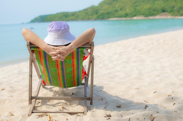 Summer beach vacation concept Asia woman with hat relaxing and arm up on chair beach at Thailand