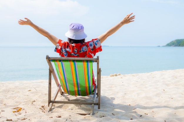 Summer beach vacation concept Asia woman with hat relaxing and arm up on chair beach at Thailand