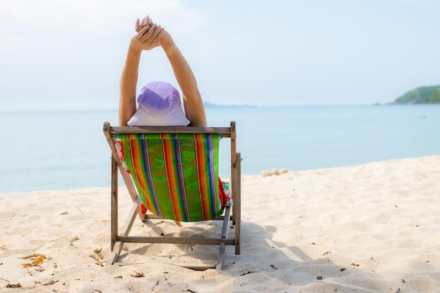 Summer beach vacation concept Asia woman with hat relaxing and arm up on chair beach at Thailand