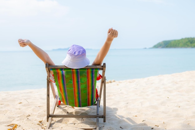 Summer beach vacation concept Asia woman with hat relaxing and arm up on chair beach at Thailand