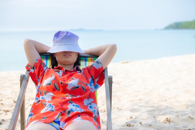 Summer beach vacation concept Asia woman with hat relaxing and arm up on chair beach at Thailand