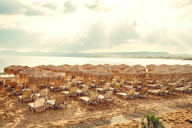 Summer beach with straw umbrellas and sunbeds Vacation and holiday concept