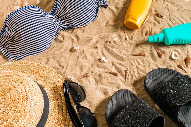 Summer bikini and accessories stylish beach set, Beach bikini summer outfit and sea sand as background, Top View, Concept