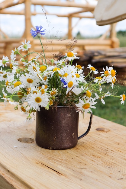 Summer bouquet of white daisies, in an iron vase, on a wooden background,wildflowers