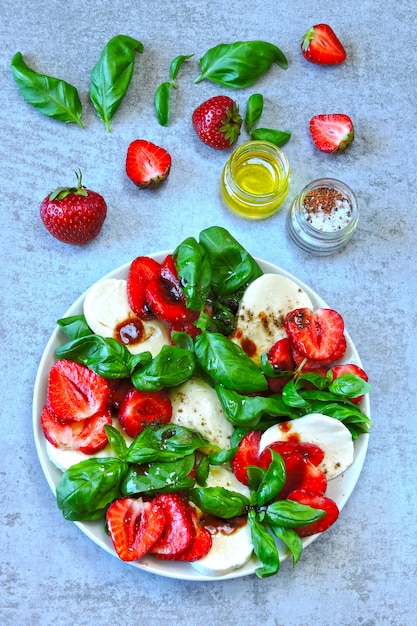 Photo summer caprese salad. caprese with strawberries. dietary salad with basil and mozzarella. keto diet.