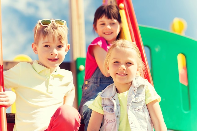 summer, childhood, leisure, friendship and people concept - group of happy kids on children playground