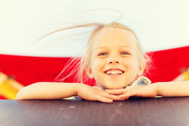 summer, childhood, leisure and people concept - happy little girl on children playground climbing frame