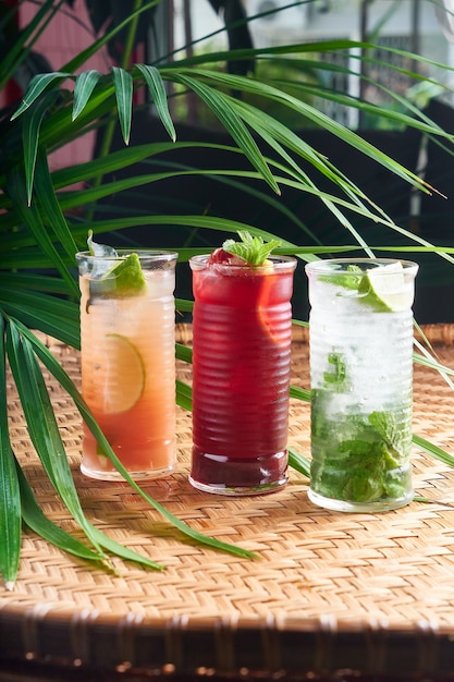 Summer chilled drinks with fresh juice, mochito, hibiscus, mango on wicker table with leaves