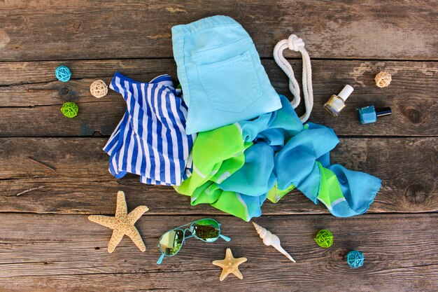      Summer clothes and accessories on old wooden background. Top view, flat lay. 