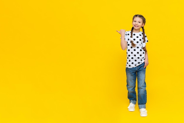 Summer clothes on a beautiful little girl A child in jeans and a polka dot Tshirt on a yellow background