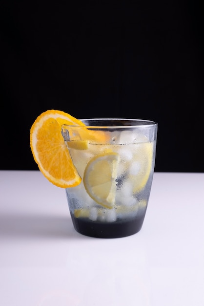 Summer cocktail in a glass on a white table and black background. minimalistic concept