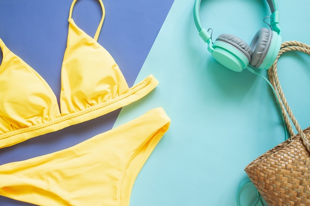 Summer collection, yellow colour bikini, headphones and straw beach bag. Summer vacation