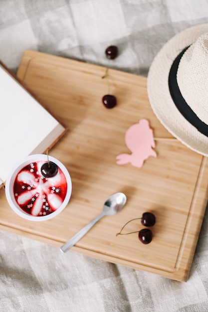 summer composition with cherry ice cream book and straw hat top view